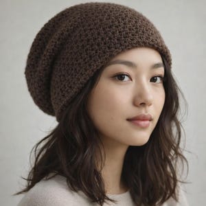 May include: A brown knit beanie hat. The hat is made of a textured, woven material and has a slouchy fit. The hat is a solid, dark brown color. The beanie is worn by a person with dark hair and a neutral-colored top.