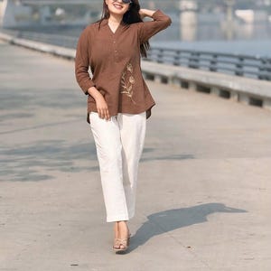 May include: A white ceramic mug with a black handle and the text "But First, Coffee" in a bold, black font. The mug is set against a blurred background, suggesting a cozy setting.