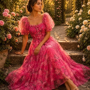 May include: A vibrant fuchsia midi dress featuring a square neckline, short puff sleeves, and a button-down bodice. The dress is crafted from a sheer, layered fabric adorned with an all-over floral print, featuring a gathered waist and a tiered skirt.
