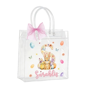Op de afbeelding: Transparante draagtas met een roze strik en transparante handvatten. De tas heeft een paasontwerp met een konijn, kuikens, eieren en de naam "Sarahlis" in roze script. De letter "S" is versierd met bloemen.