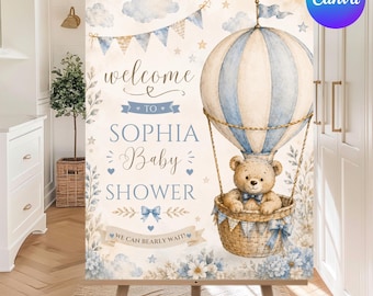 May include: A rectangular sign featuring a watercolor illustration of a teddy bear in a blue and cream hot air balloon. The text reads: welcome TO SOPHIA Baby SHOWER WE CAN BEARLY WAIT! The design includes blue bunting, stars, and floral accents.