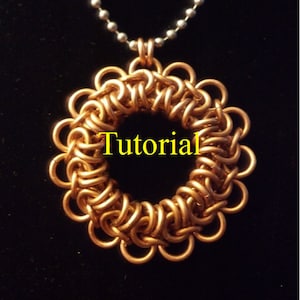 Puede incluir: Un colgante de malla de cadena de cobre en forma de círculo con una cadena de plata unida. El colgante está hecho de pequeños anillos de metal entrelazados. La palabra "Tutorial" está escrita en texto amarillo en el centro del colgante.