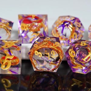 Puede incluir: Juego de siete dados poliédricos con base de resina transparente, con detalles morados y dorados. Cada dado tiene números dorados y un anillo dorado decorativo. Ideal para juegos de mesa.