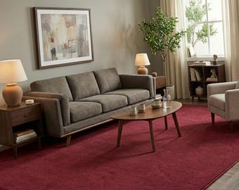 May include: A living room featuring a brown sofa, a deep red rug, and a wooden coffee table. Two lamps are on wooden side tables. An abstract painting in a frame hangs on the wall. A small tree and a window with curtains are visible.