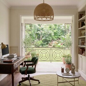 Puede incluir: Una oficina en casa con un escritorio de madera oscura con computadora, una silla giratoria tapizada en verde, una alfombra redonda verde oliva, una mesa de centro circular, una l&aacute;mpara colgante tejida y estanter&iacute;as integradas.