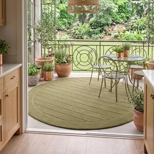 Puede incluir: Escena de patio al aire libre con una alfombra redonda verde oliva con dise&ntilde;o texturizado. Una mesa con tapa de cristal y sillas est&aacute;n dispuestas en el patio, rodeadas de plantas en macetas y una l&aacute;mpara colgante tejida.