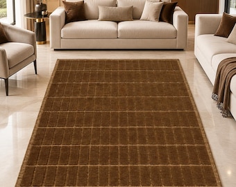 May include: A rectangular area rug featuring a deep brown colour and a structured grid pattern composed of raised, uniform rectangular segments. The rug has a consistent texture throughout its surface and is finished with a simple, clean border.