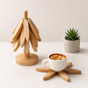 May include: A light brown wooden tree-shaped coaster set with multiple detachable petal-shaped pieces. The pieces are arranged to form a vertical tree structure or laid flat as individual coasters under a white ceramic cup with coffee.