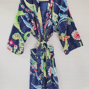 Peut inclure: Peignoir matelassé bleu marine avec un motif floral aux tons de rouge, jaune, vert et bleu. Le peignoir a des manches longues et une fermeture à nouer. Le tissu est cousu avec du fil blanc.