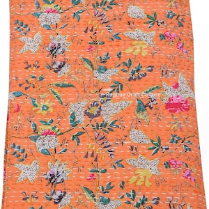 Może przedstawiać: Pomarańczowa, kwiatowa kołdra z bogatym wzorem kwiatów i liści w odcieniach różu, zieleni, bieli i żółci. Kołdra posiada skomplikowane przeszycia i tekst "Raghav Craft Culture".