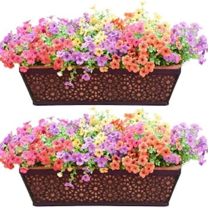 May include: Two rectangular brown planters filled with colorful artificial flowers. The flowers are a mix of pink, purple, orange, and yellow. The planters have a decorative geometric pattern.