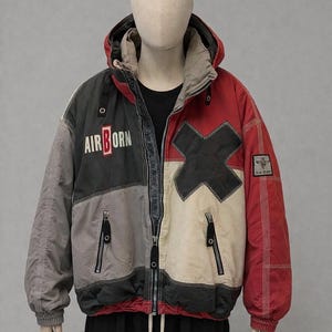 May include: A color-blocked winter jacket with a hood. The jacket features panels of gray, black, off-white, and red. The text "AIR BORN" is printed on the left chest. The jacket has a full zipper and two front pockets.
