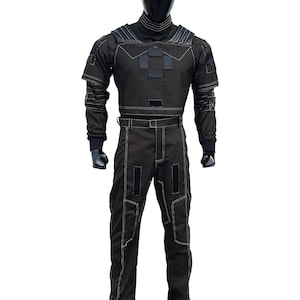 May include: Black jumpsuit with white stitching details. The outfit features a high collar, padded shoulders, and a belt. The long-sleeved top has a geometric design on the chest. The pants have rectangular patches and a straight leg design.