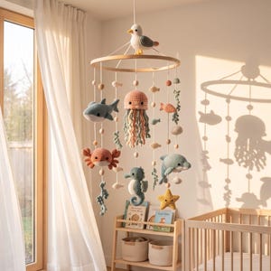 Può includere: Una giostrina sospesa con una cornice circolare in legno e un gabbiano all'uncinetto sulla sommità. Dal telaio pendono varie creature marine all'uncinetto, tra cui uno squalo, una medusa, un granchio, un cavalluccio marino, un delfino e una stella marina.