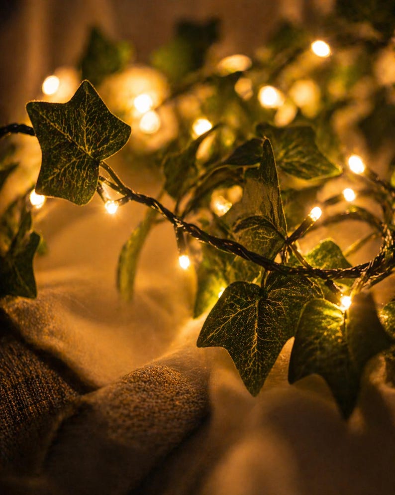 May include: A string of warm white LED lights intertwined with artificial ivy leaves. The leaves are a deep green with detailed veining, creating a natural look. The lights are evenly spaced, providing a soft, ambient glow. Ideal for home decor.