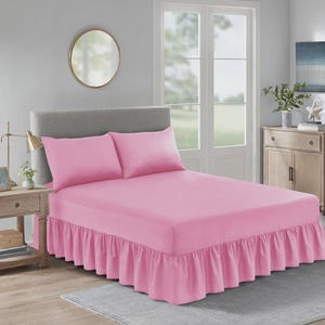 Può includere: Un completo letto rosa con una gonna a balze e due federe abbinate. Il letto è fatto. La stanza ha una combinazione di colori neutri, uno specchio rotondo e un comodino.