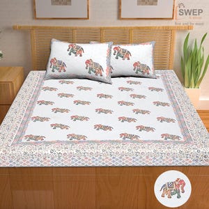 May include: A white bed sheet and two matching pillowcases featuring a repeating pattern of multi-colored elephants with intricate geometric designs. The set includes a decorative border with a small floral print and a zigzag line pattern.