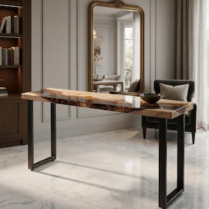 Puede incluir: Una mesa consola rectangular con un tablero de madera natural de borde vivo y una incrustación de resina oscura en el centro. La mesa se apoya sobre dos patas de metal negro en forma de U, proporcionando una base estable a la superficie.