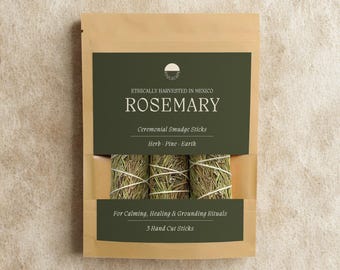 May include: A tan paper pouch containing three rosemary ceremonial smudge sticks tied with white string. The dark green label reads: Ethically Harvested In Mexico, Rosemary, Ceremonial Smudge Sticks, Herb, Pine, Earth, For Calming, Healing & Grounding Rituals, 5 Hand Cut Sticks.