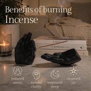 May include: Two matte black hand-shaped incense holders, one upright and one horizontal, with a thin incense stick. Text reads: Benefits of burning Incense, reduced stress, mental clarity, improved sleep, cleansed air. Books and a candle are visible.