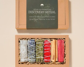 May include: A rectangular cardboard gift box containing six bundles of dried herbs and wood. The dark green label reads DISCOVERY RITUAL, EXPLORE YOUR INNER LANDSCAPE, and lists White Sage, Rosemary, Lavender Sage, Rose Sage, and Palo Santo.