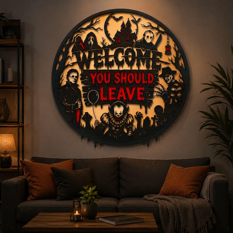 May include: A circular black wall sign featuring backlit horror movie characters and the text WELCOME YOU SHOULD LEAVE. The design includes silhouettes of a haunted house, trees, and iconic figures like a clown with a balloon and masked slashers.