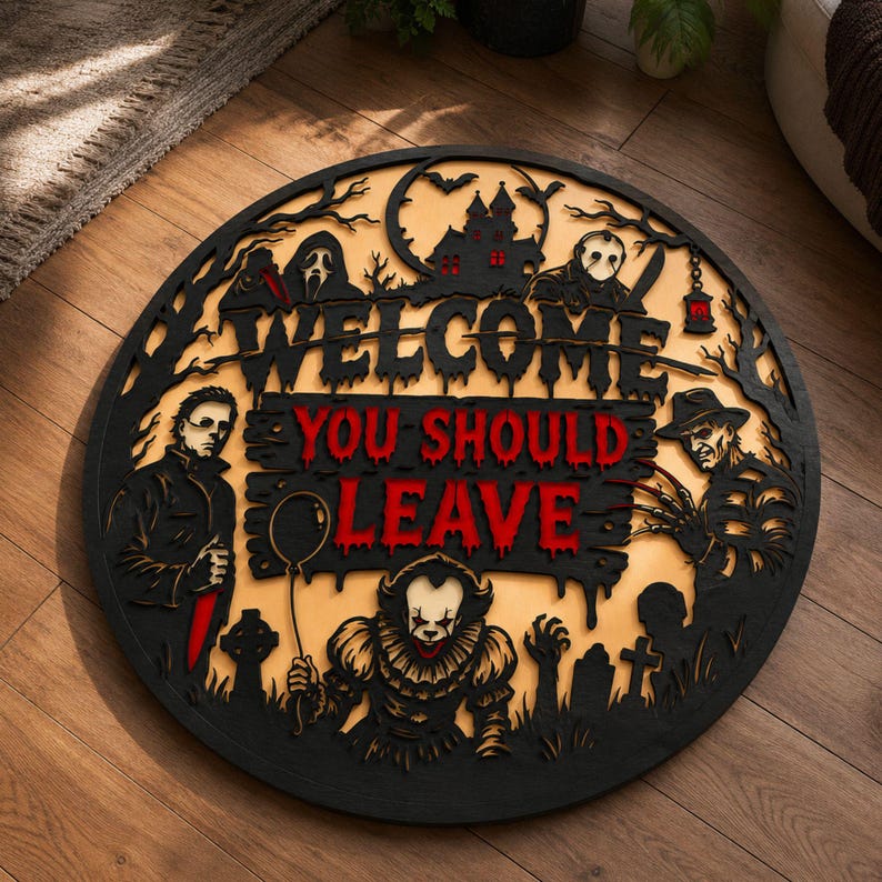 May include: A circular wooden wall sign featuring black silhouettes of horror movie characters and a haunted house. The text reads WELCOME in black and YOU SHOULD LEAVE in red. The design includes figures like a clown, a masked slasher, and a zombie.