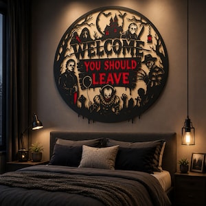 May include: A circular black wall sign featuring horror movie characters and the text WELCOME YOU SHOULD LEAVE in red. The design includes silhouettes of a haunted house, trees, and iconic figures like a clown with a balloon, all set against a light background.