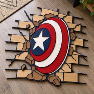 Puede incluir: Una pieza de arte mural de madera multicapa que representa un escudo circular con una estrella blanca central sobre un campo azul, rodeado de anillos rojos y blancos. El escudo parece atravesar una pared de ladrillos marrón claro con bordes azul oscuro.