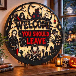 May include: A circular black wall sign with a backlit design featuring horror movie characters, a haunted house, and the text "WELCOME YOU SHOULD LEAVE" in red and black. The sign depicts figures including a clown, a masked slasher, and a clawed villain.
