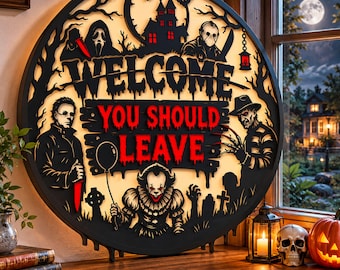 May include: A circular black wall sign with a backlit design featuring horror movie characters, a haunted house, and the text "WELCOME YOU SHOULD LEAVE" in red and black. The sign depicts figures including a clown, a masked slasher, and a clawed villain.