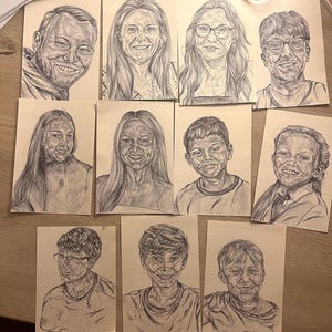 May include: A collection of pen and ink portraits on rectangular paper. The portraits depict various people, each with unique facial features and expressions. The drawings are detailed, showcasing the artist's skill in capturing likenesses.