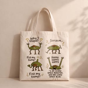 Puede incluir: Bolso tote de lona color crema con cuatro ilustraciones de extraterrestres de dibujos animados y texto humorístico. Los extraterrestres son verdes con detalles marrones, con frases como "¿Por qué, estúpido?" y "¡Choca esos cinco!"