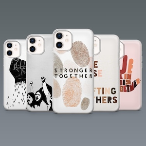 Op de afbeelding: Een verzameling van vijf telefoonhoesjes met verschillende ontwerpen. Eén hoesje heeft een zwarte vuist, een ander een zwart-wit illustratie van een menigte, en een derde toont vingerafdrukken met de tekst "STRONGER TOGETHER". De overige hoesjes hebben tekst en handafbeeldingen.