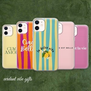 Op de afbeelding: Een verzameling telefoonhoesjes met diverse ontwerpen. Eén hoesje is geel met de tekst "CIAO AMORI", een ander is oranje en roze met de tekst "Ciao Bell", en een derde heeft gele en blauwe strepen met "la dolce vita".