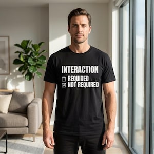May include: Black crew neck t-shirt with the white text "INTERACTION REQUIRED ☐ NOT REQUIRED ☑". The t-shirt is being worn by a person.