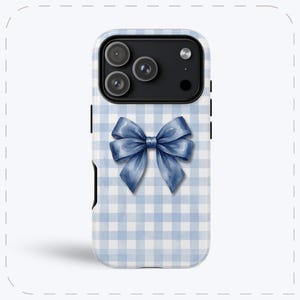 Pode incluir: Capa de telefone com um padrão xadrez vichy azul e branco e um laço azul em estilo aquarela. A capa tem um recorte para um sistema de câmera com várias lentes.