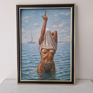 May include: An oil painting in a black and gold frame depicting a figure standing in the ocean, wearing leopard print bikini bottoms and a white t-shirt pulled over their head, with one arm raised making a middle finger gesture against a blue sky.
