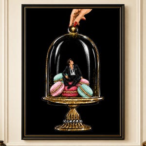 Könnte beinhalten: Ein gerahmter Wandkunstdruck, der eine Person im schwarzen Anzug zeigt, die auf einem Haufen bunter Macarons in einer Glasglocke sitzt. Die Glocke steht auf einem goldenen Sockel, und eine Hand mit rotem Nagellack hebt den Deckel vor schwarzem Hintergrund.