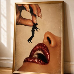 Könnte beinhalten: Ein gerahmter surrealistischer Kunstdruck, der eine große Hand mit glitzernden Fingernägeln zeigt, die eine winzige Person im schwarzen Anzug über einem offenen Mund mit glitzernden roten Lippen hält. Das Bild hat einen warmen Beigeton.