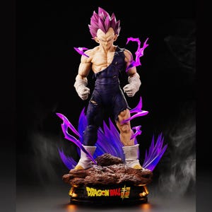 May include: A detailed figurine of a character with spiky purple hair and torn dark blue clothing. The figure stands on a rocky base with purple energy effects and the words "DRAGON BALL SUPER". The background is black.