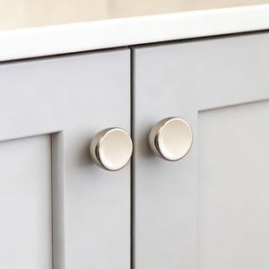 Può includere: Una tazza di ceramica bianca con manico nero e la scritta "But First, Coffee" in nero, in grassetto. La tazza è appoggiata su una superficie bianca.