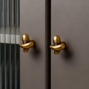 May include: A white ceramic mug with a black handle and the text "But First, Coffee" in a black, bold font. The mug is on a white surface.