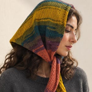 Könnte beinhalten: Ein dreieckiges Strickkopftuch mit horizontalen Streifen in Senfgelb, Waldgrün, Blaugrün, Violett und Terrakotta-Orange. Das Accessoire wird unter dem Kinn mit zwei spitz zulaufenden Enden gebunden und zeigt ein strukturiertes Strickmuster.