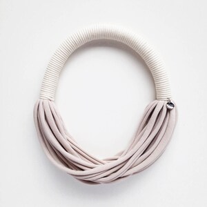 May include: A beige fabric necklace with a white rope detail and a small silver tag that says "MINA".