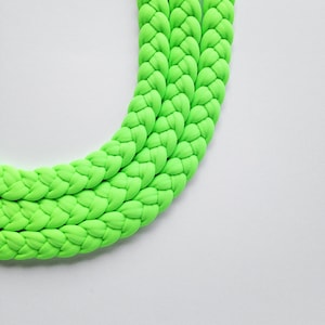May include: A bright green braided rope made of soft fabric. The rope is thick and has a smooth texture.