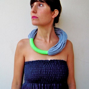 Puede incluir: Una mujer con un vestido azul sin tirantes y un collar de tela gris y verde brillante.