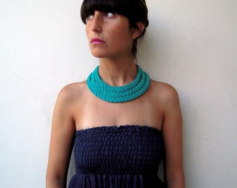 May include: A woman with dark hair is wearing a strapless blue dress and a turquoise braided necklace.