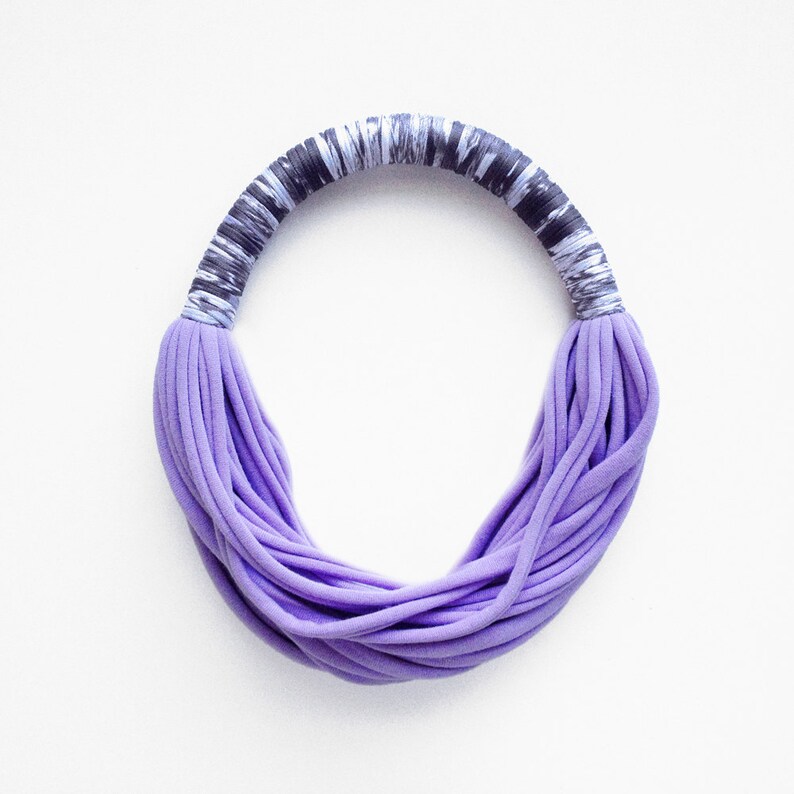 Peut inclure: Un collier en tissu violet et noir avec un design &eacute;pais et superpos&eacute;. Le collier est fait d'un tissu doux et extensible et est parfait pour ajouter une touche de couleur &agrave; n'importe quelle tenue.