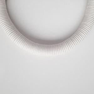 May include: A white, braided rope in the shape of a circle.